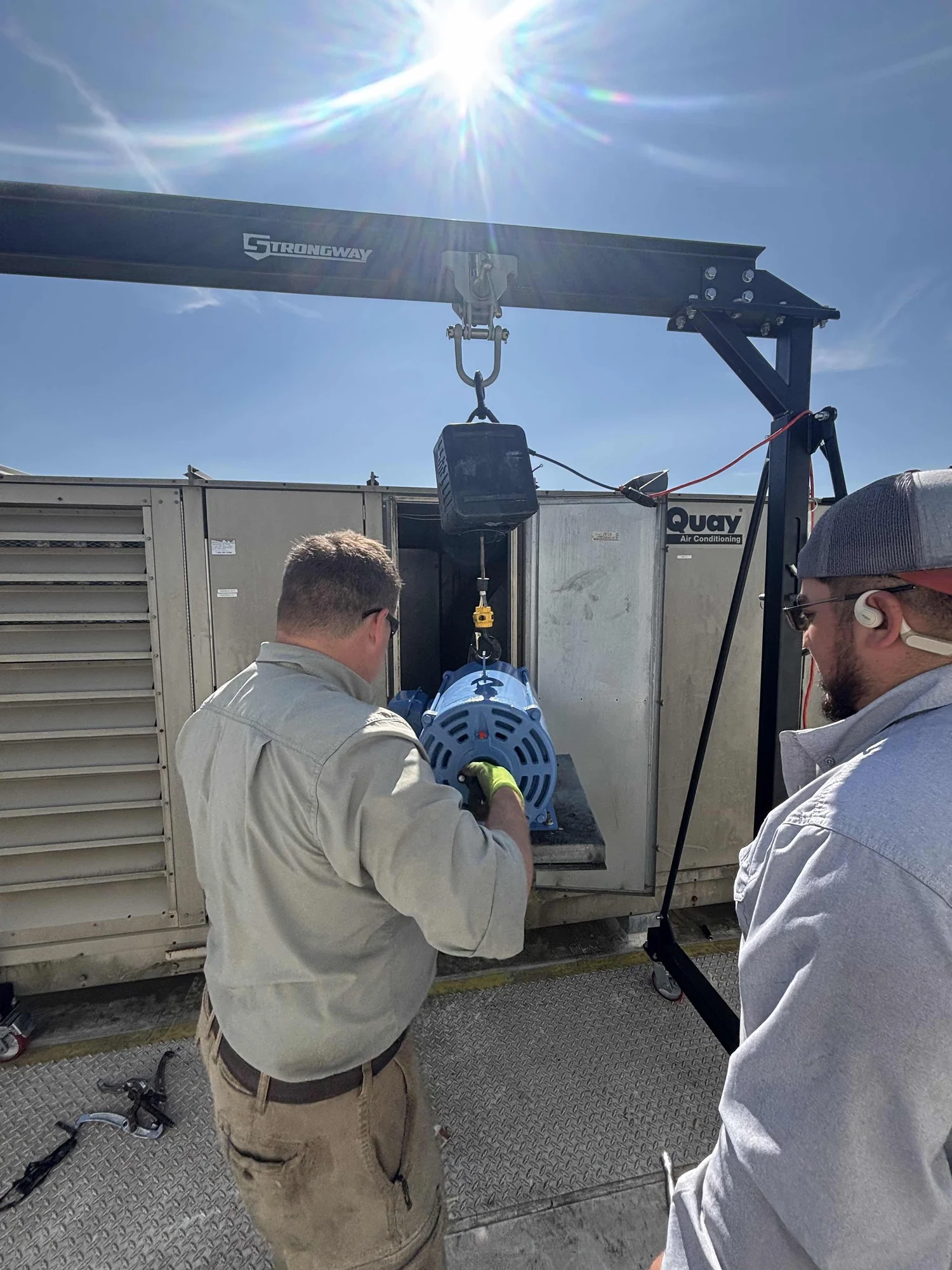 MMS technicians hoisting a motor on a rooftop unit